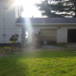Firefighters mask up to enter the garage to extinguish the roof fire